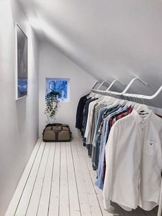 an attic closet with clothes hanging on rails