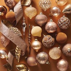 many different types of christmas ornaments are arranged on a brown surface with ribbons and decorations around them