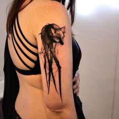 a woman with a black and white tattoo on her arm, showing the back of her shoulder