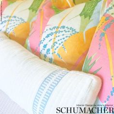 a close up of a pillow on a bed with colorful pillows and blankets behind it