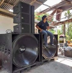 a man sitting on top of a large speaker in a room filled with other items