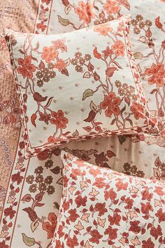 four pillows on top of each other with red and brown floral designs in the middle