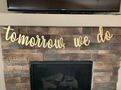 a fire place with a television above it and some writing on the fireplace mantel