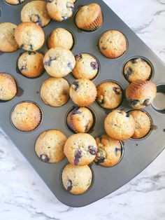 blueberry muffins sitting in a muffin tin on a marble counter top