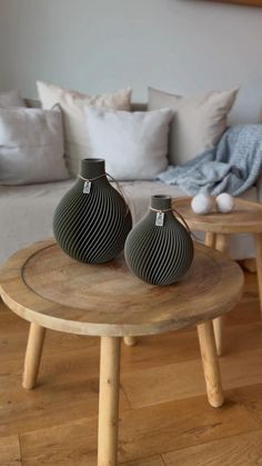 two black vases sitting on top of a wooden table in front of a couch