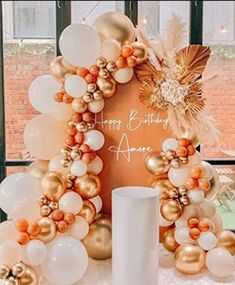 a happy birthday sign surrounded by balloons and streamers on a table in front of a window