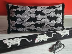 a black and white crocheted pillow with two pairs of scissors next to it