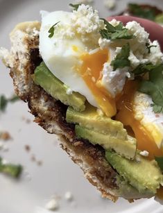 an egg and avocado sandwich is being held up by someone's hand