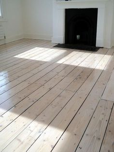 an empty room with wood floors and a fireplace