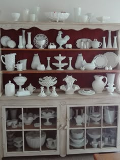 an old china cabinet is filled with white dishes and vases