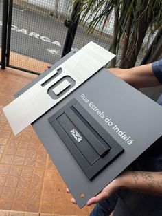 a man holding up a metal sign with the letter d on it's side