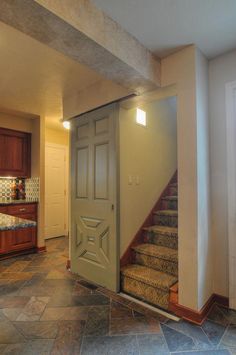 an open door leading to a kitchen with granite flooring and wooden cabinets in the background