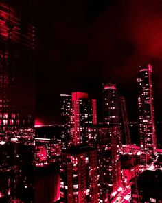 the city is lit up at night with red lights on it's buildings and skyscrapers