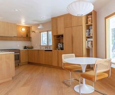 a kitchen with wooden cabinets and white table in the center, surrounded by two chairs