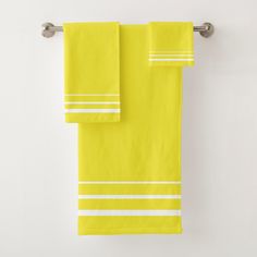 two yellow towels hanging on a towel rack in front of a white wall with text that reads, all hands on deck yellow by carry creations