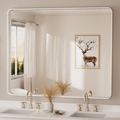 a bathroom with two sinks and a large mirror over the sink that has deer on it