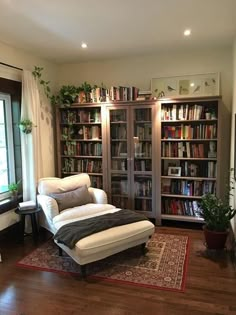 a living room filled with furniture and a book shelf next to a window covered in books