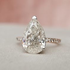 a pear shaped diamond ring sitting on top of a table