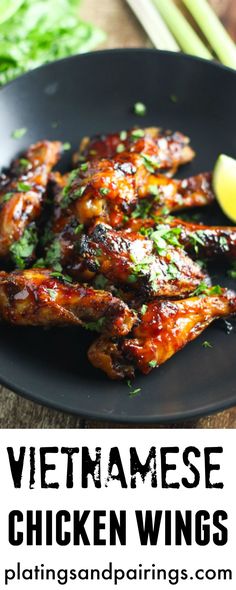 vietnamese chicken wings on a black plate with lemon wedges