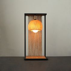 a lamp that is sitting on top of a wooden table next to a white wall