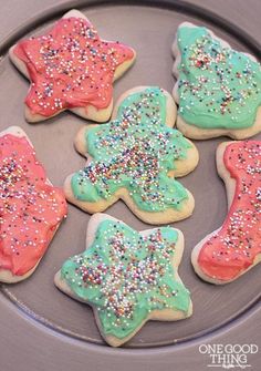 decorated cookies on a plate with sprinkles and frosting in the shape of stars