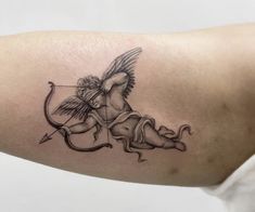 a woman's arm with an arrow and cupid tattoo on it