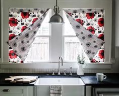 a kitchen sink under a window with red flowers on the valance and black counter tops