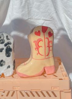 two ceramic cowboy boots sitting on top of a plastic crate with white and red paint