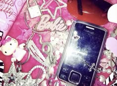 a cell phone sitting on top of a table covered in charms and other items next to it