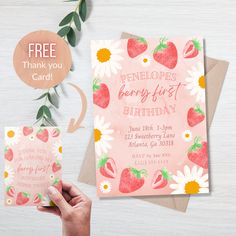 a hand holding up a pink birthday card with strawberries and daisies on it