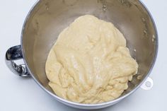 a metal bowl filled with batter on top of a table