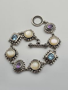 Vintage 925 Silver Blue Topaz, Mother of Pearl, and Amethyst Bracelet Item w#3641 Clean and in good condition marked 925  31.8 grams 8-Inches long with a toggle style clasp Welcome to Westgate Jewels!! We specialize in vintage estate, designer, and fine jewelry. Our shop consists of items that are estate, antique, and / or vintage conditions unless otherwise noted. This means that most items are prior owned and may have some imperfections such as light scratches, scuffs, and / or patina. Our ite Elegant Sterling Silver Multi-stone Bracelet, Elegant Multi-stone Sterling Silver Bracelet, Sterling Silver Bracelet With Gemstone Accents, Pearl And Amethyst, Mother Of Pearl Bracelet, Toggle Clasp Bracelet, Vintage Native American Jewelry, Vintage Designer Jewelry, Gems Bracelet