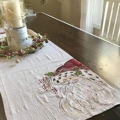 a white table cloth with a santa clause on it and some candles in the background