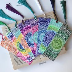 six different colored tassels are sitting on top of an open book, with the string attached to them