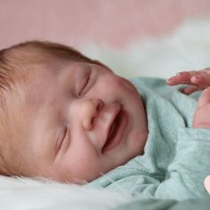 a close up of a baby laying on top of a bed with its eyes closed