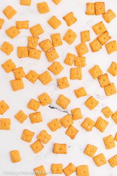 cheeto crackers are scattered on a white countertop, with the top one being cut into smaller squares