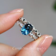 a woman's hand holding an engagement ring with blue and white stones