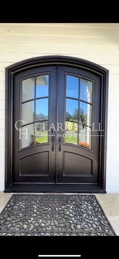 the front door to a house with two double doors and a black mat on it