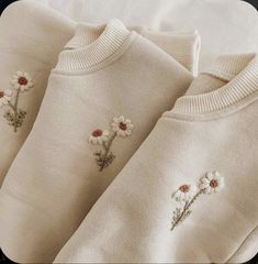 three sweaters with daisies embroidered on them