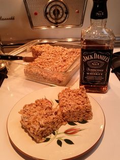 a plate with some food on it next to a bottle of jack daniels