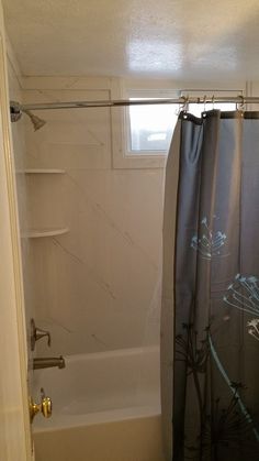 a bath tub sitting next to a shower curtain