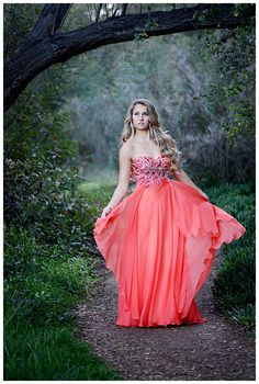 a woman in an orange dress walking down a path