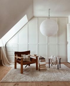 a room with a chair, lamp and books on the floor in front of it