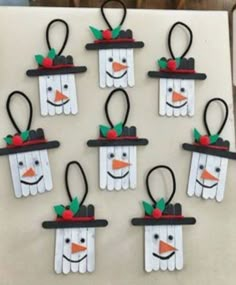 snowmen made out of popsicle sticks are hanging on the wall