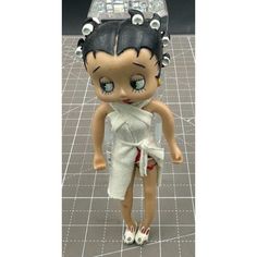 the doll is wearing a white dress and has her hair in a bunt style