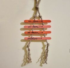 four wooden sticks with writing on them hanging from a string attached to a white wall