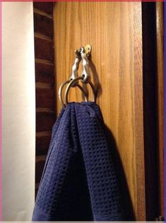 a towel is hanging on a hook in a wooden door with a blue towel draped over it