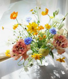 a vase filled with lots of different colored flowers