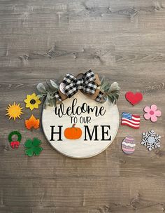 a welcome to our home sign surrounded by magnets and paper flowers on a wooden surface