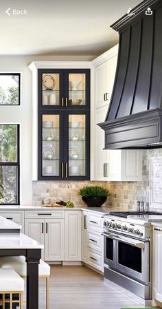 a kitchen with white cabinets and black stove top oven, counter tops, and chairs